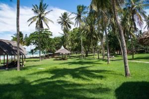 un campo de hierba con palmeras y el océano en Cocoa Luxury Resort, Nyali, Mombasa, en Mombasa