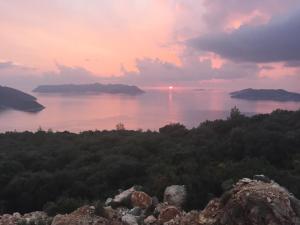 um pôr-do-sol sobre uma massa de água com ilhas em Derya Beach Apartment em Kas