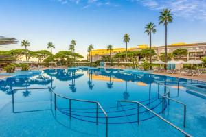 a large swimming pool at a resort with palm trees at Valentin Sancti Petri in Chiclana de la Frontera