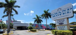 um sinal para um concessionário de carros com palmeiras num parque de estacionamento em Fort Lauderdale Grand Hotel em Fort Lauderdale