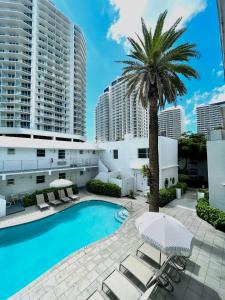 uma piscina com cadeiras e uma palmeira e edifícios em Aqua Hotel em Fort Lauderdale