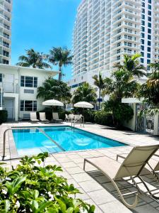 uma piscina com cadeiras e guarda-sóis e um edifício em Aqua Hotel em Fort Lauderdale