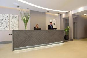 two people standing at a reception desk in a lobby at Believe Madero Hotel in Buenos Aires