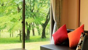 a couch with red pillows sitting in front of a window at Izu Ippeki lake Side Terrace - Vacation STAY 32475v in Ito