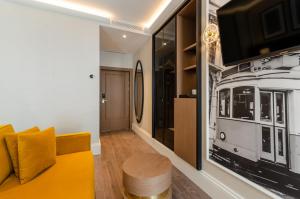 a living room with a yellow couch and a tv at Eurostars Lisboa Baixa in Lisbon