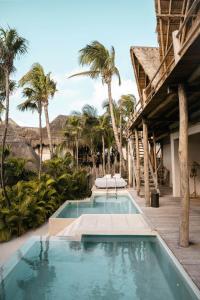 - une piscine à côté d'un complexe avec des palmiers dans l'établissement La Valise Tulum, member of Small Luxury Hotels, à Tulum