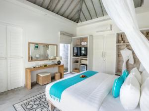 een slaapkamer met een groot bed met blauwe en witte kussens bij Kardia Resort Gili Trawangan A Pramana Experience in Gili Trawangan