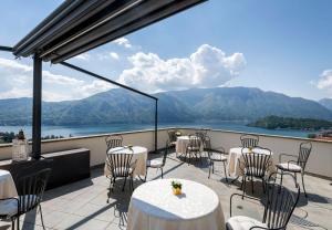 a balcony with tables and chairs and a view of the mountains at Hotel La Perla in Tremezzo