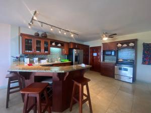 a kitchen with a large island with bar stools at Los Porticos in Placencia Village