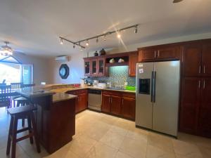 a kitchen with wooden cabinets and a stainless steel refrigerator at Los Porticos in Placencia Village