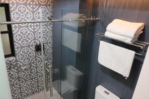 een badkamer met een glazen douche, een toilet en handdoeken bij The Lu'um House in Tuxtla Gutiérrez