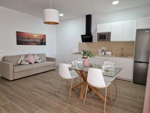 a kitchen and living room with a glass table and white chairs at Alojamientos Agaete Pueblo Nº4 y Nº5 in Agaete