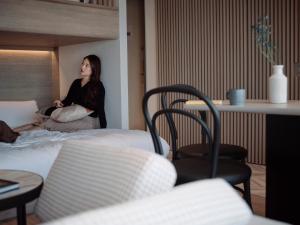 uma mulher sentada numa cama num quarto de hotel em fav HIROSHIMA HEIWAODORI em Hiroshima