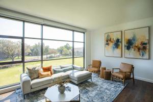 een woonkamer met een bank, stoelen en ramen bij Drey Hotel in Dallas