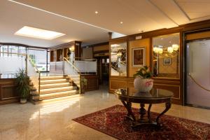 a lobby with a table and stairs and a staircase at Hotel Il Chiostro by LVG Hotel Collection in Verbania