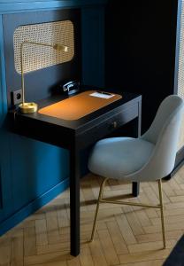 a desk with a lamp and a white chair at HANNONG Hotel & Wine Bar in Strasbourg