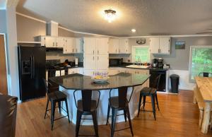 a kitchen with white cabinets and a island with bar stools at Bear Doodle 2.0 in Sevierville