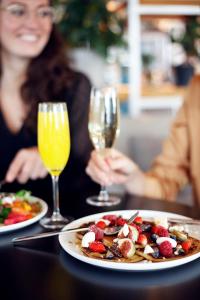 une femme assise à une table avec une assiette de nourriture et des verres à vin dans l'établissement Zoku Amsterdam, à Amsterdam