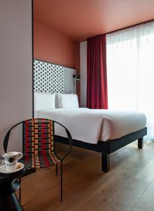 a bedroom with a large bed and a chair at BOMA easy living hotel in Strasbourg