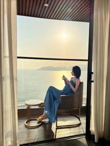 une femme assise sur une chaise devant une fenêtre dans l'établissement La Vague Hotel, à Nha Trang