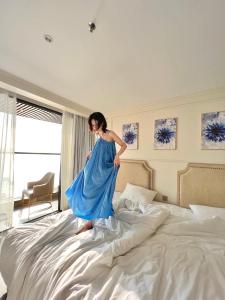 une femme en robe bleue debout sur un lit dans l'établissement La Vague Hotel, à Nha Trang