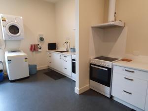 a kitchen with white cabinets and a sink and a stove at Travel Stay City Hostel in Dunedin