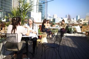 a group of people sitting at tables on a rooftop at Rena's House in Tel Aviv