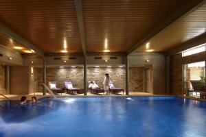 a woman standing next to a large swimming pool at The Greenway Hotel & Spa in Cheltenham