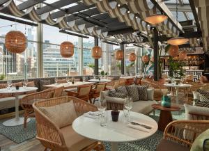 a restaurant with tables and chairs and windows at Virgin Hotels London - Shoreditch in London