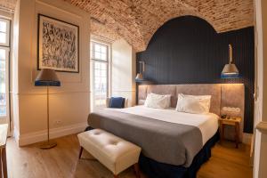 a bedroom with a large bed and a brick wall at Boemio FLH Hotels in Lisbon