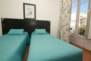 two twin beds in a room with a window at Residencial Joao XXI in Lisbon