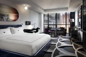 um quarto de hotel com uma cama branca e uma secretária em Bisha Hotel Toronto em Toronto