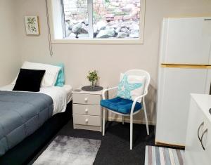 a bedroom with a bed and a chair and a window at Travel Stay City Hostel in Dunedin