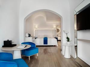 ein Hotelzimmer mit einem Bett, einem Tisch und Stühlen in der Unterkunft Katikies Santorini - The Leading Hotels Of The World in Oia