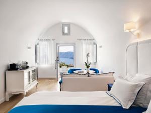 ein Hotelzimmer mit 2 Betten und einem Fenster in der Unterkunft Katikies Santorini - The Leading Hotels Of The World in Oia