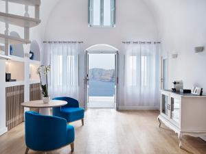 ein Wohnzimmer mit einem Tisch und blauen Stühlen in der Unterkunft Katikies Santorini - The Leading Hotels Of The World in Oia