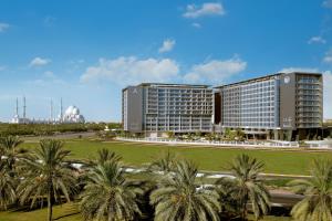 um grande edifício com palmeiras em frente em Park Rotana Abu Dhabi em Abu Dhabi