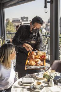 a man preparing a tray of pastries on a table at Zocalo Central & Rooftop Mexico City in Mexico City