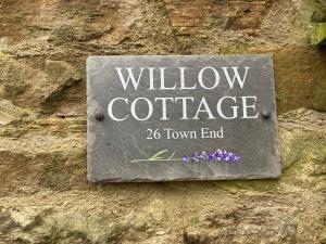 ミドルトン・イン・ティーズデールにあるWillow Cottageの窓付きのコテージのある石壁のサイン