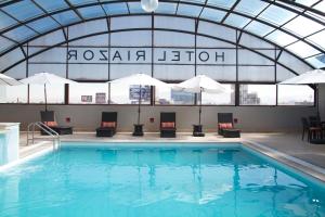 a pool with chairs and umbrellas in a building at Hotel Riazor Aeropuerto in Mexico City