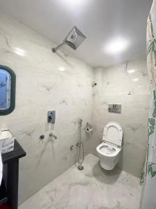 uma casa de banho branca com um WC e um chuveiro em Kashi Dham Home Stay em Varanasi