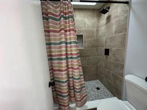 a bathroom with a shower curtain next to a toilet at Beautiful House Sleeps 12 - Hot Tub - Breakfast - Walk to Beach in Panama City Beach