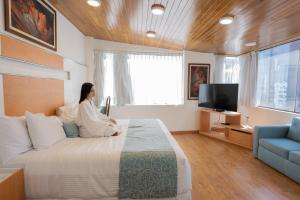 a woman sitting on a bed in a bedroom at Suites Coben Apartamentos Amueblados in Mexico City