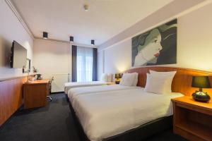 ein Hotelzimmer mit 2 Betten und einem Gemälde an der Wand in der Unterkunft Leonardo Hotel Utrecht City Center in Utrecht