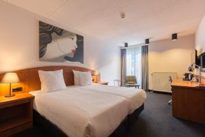 ein Hotelzimmer mit einem großen Bett und einem Fenster in der Unterkunft Leonardo Hotel Utrecht City Center in Utrecht