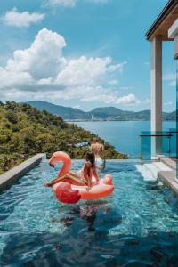 a little girl riding on an inflatablevisor in a swimming pool at Wyndham Grand Phuket Kalim Bay in Patong Beach