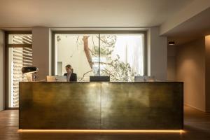 a woman sitting at a reception desk in an office at Hotel Promessi Sposi in Malgrate