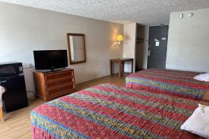 a hotel room with two beds and a flat screen tv at Kampus Inn by OYO Gainesville - University Area in Gainesville