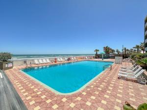 a swimming pool with chairs and the ocean in the background at Boardwalk Inn and Suites in Daytona Beach