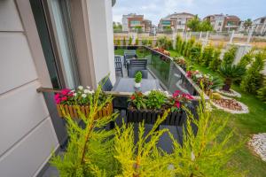 uma varanda com flores e plantas num edifício em LARA MARİNE HOMES em Antália